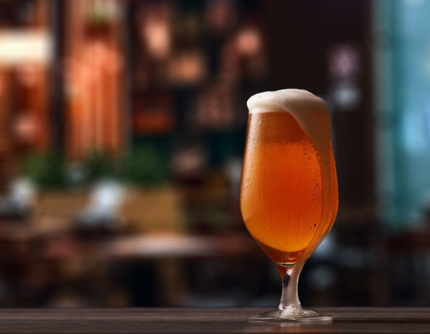 Beer in a glass with the foam spilling over the right-hand side 