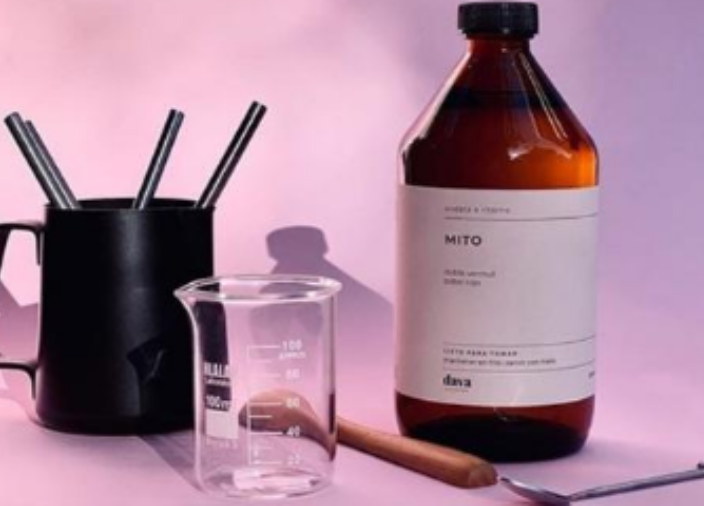 Dark bottle of liquid with measuring beaker and jug holding metal straws