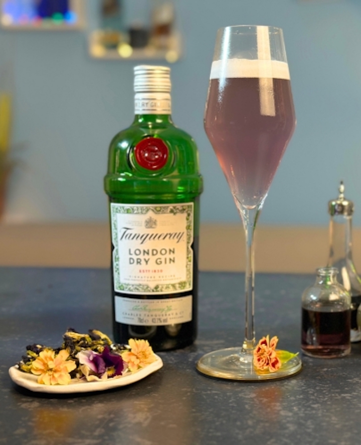 Cocktail steht neben einer Flasche und einem Teller