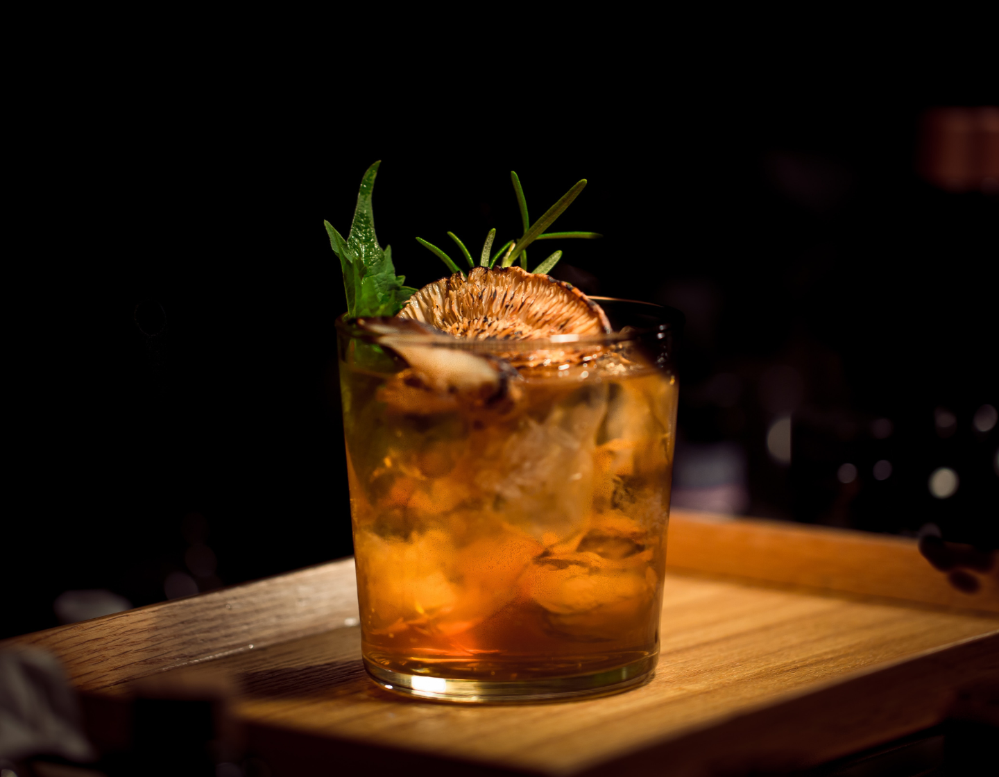Vaso de ron con hielo y adorno de romero.