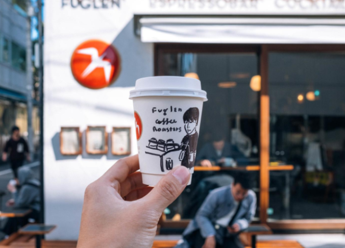 Hand holding coffee cup outside Fuglen, Tokyo 