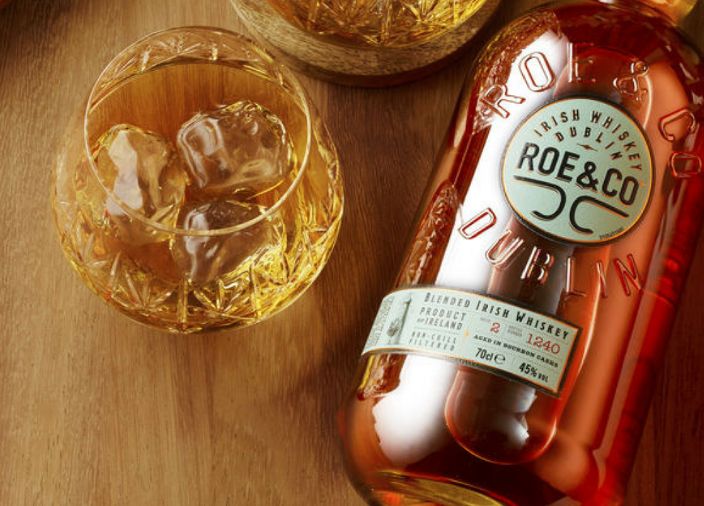 Bottle of Roe and Co lying beside a whiskey serve in whiskey glass with ice