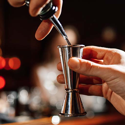 Close up shot of liquid being poured into a jigger.