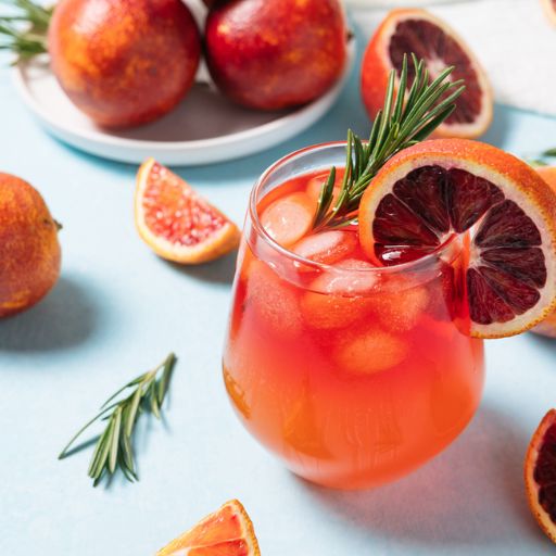 Vaso de tubo con cóctel de naranja sin alcohol con frutas frescas y decoración.