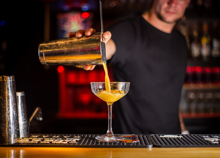 Bartender vertiendo cóctel con coctelera