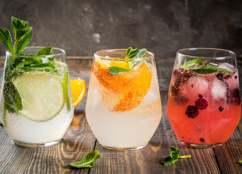 Três gins servidos em copos com guarnição