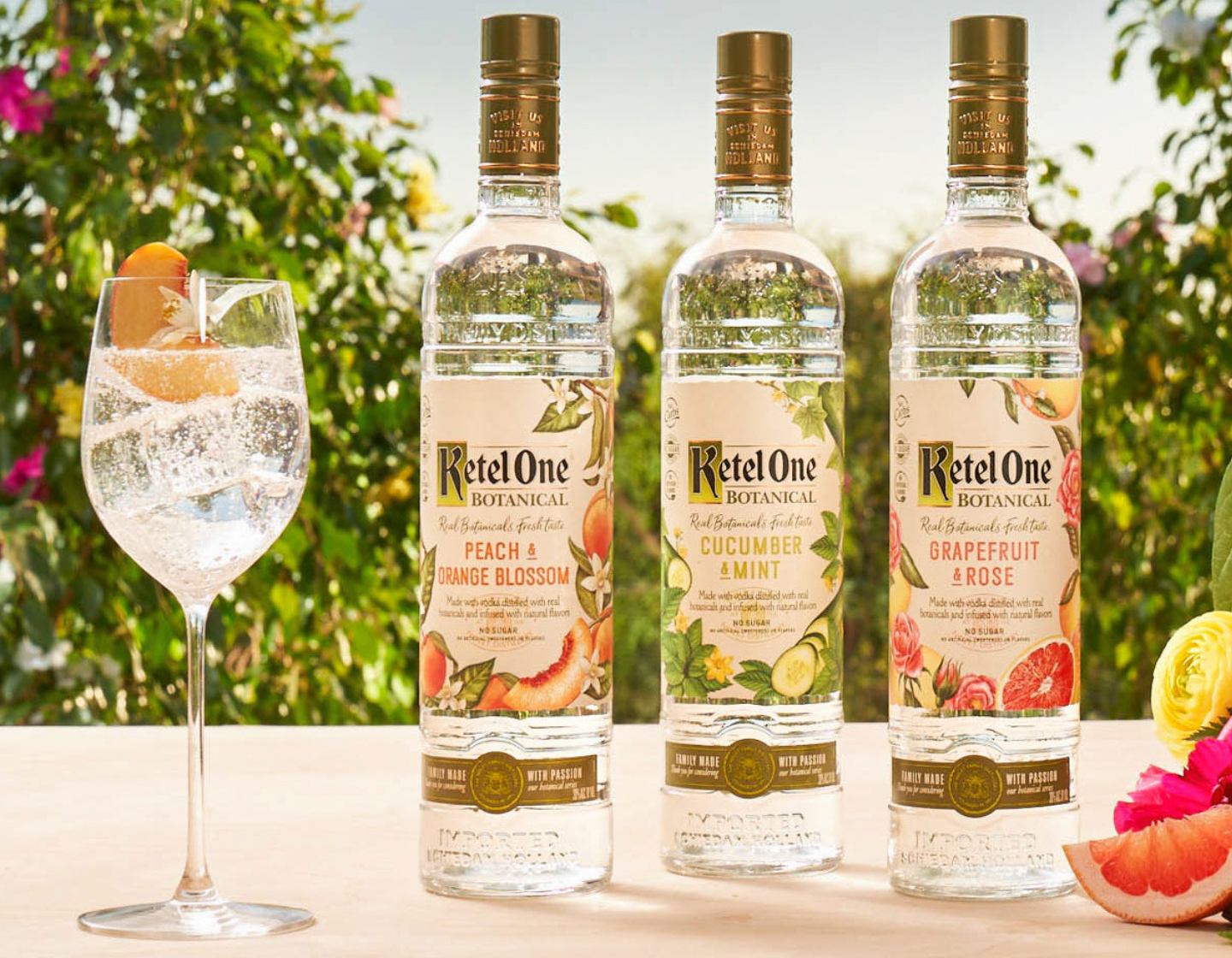 Seleção de variantes Ketel One Botanical sobre uma mesa com folhagens ao fundo