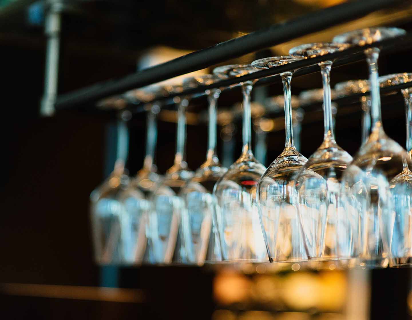 Glasses neatly organised on a rack behind bar