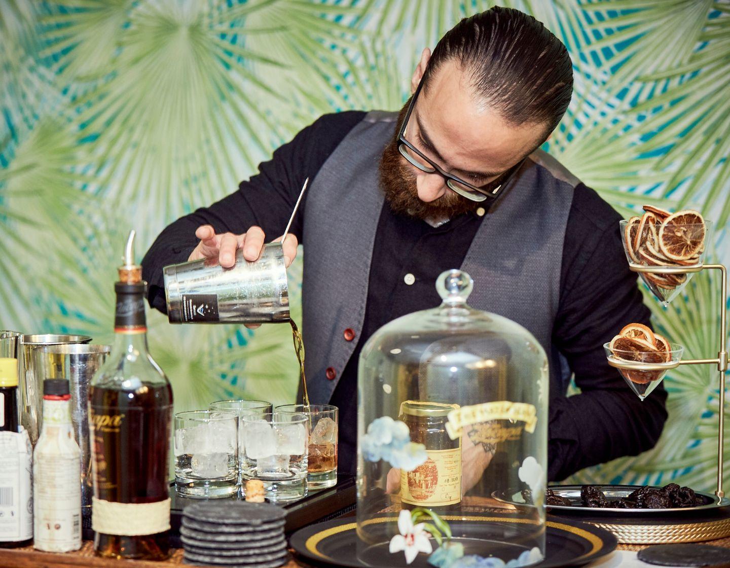 Hombre sirviendo una bebida utilizando herramientas de bar.