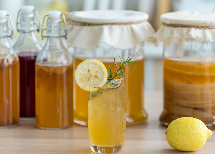 Cocktail glass with fermented liquids in jars behind it