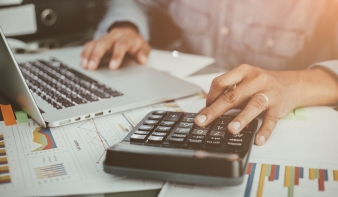 Persona usando calculadora y portátil para hacer un presupuesto