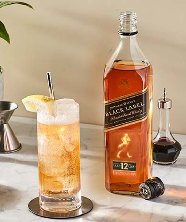 Botella de Johnnie Walker Black Label junto a highballs y herramientas de bar.