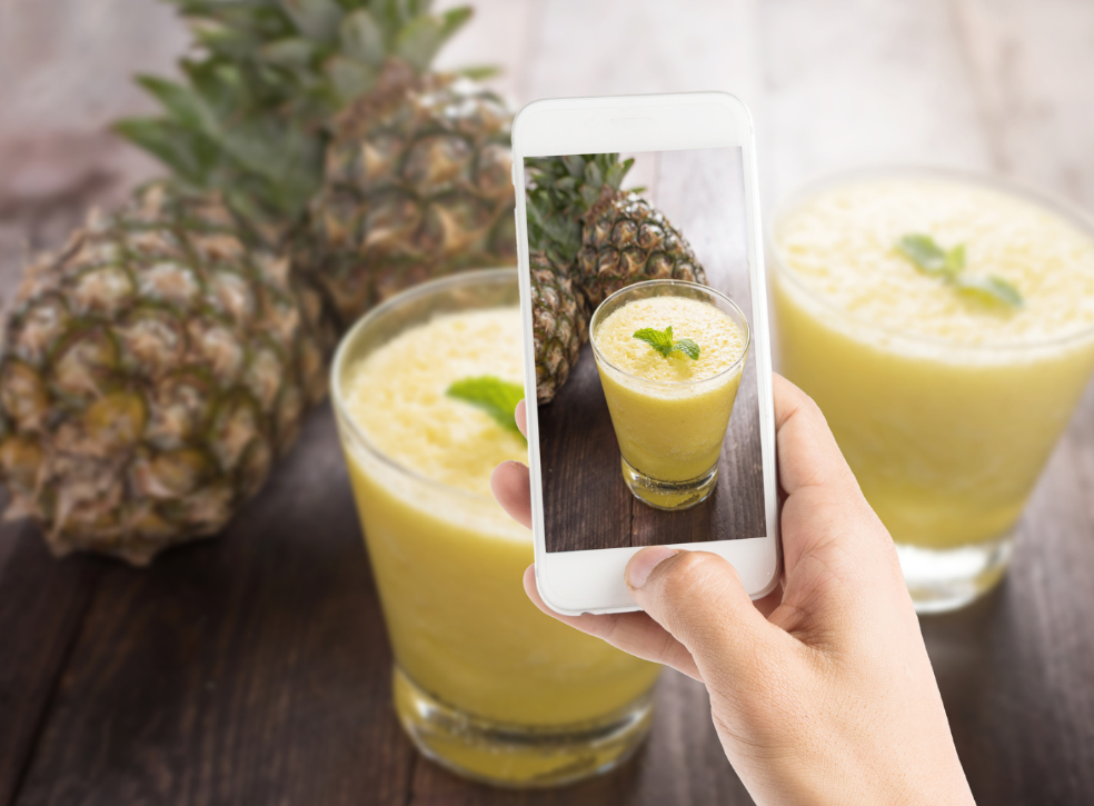 Bartender tomando una foto de una bebida con su teléfono