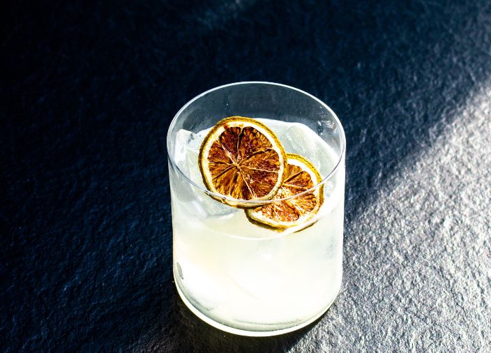 Ein trüber Drink in einem kurzen Becherglas mit zwei Trockenfruchtgarnituren auf dem Eis.