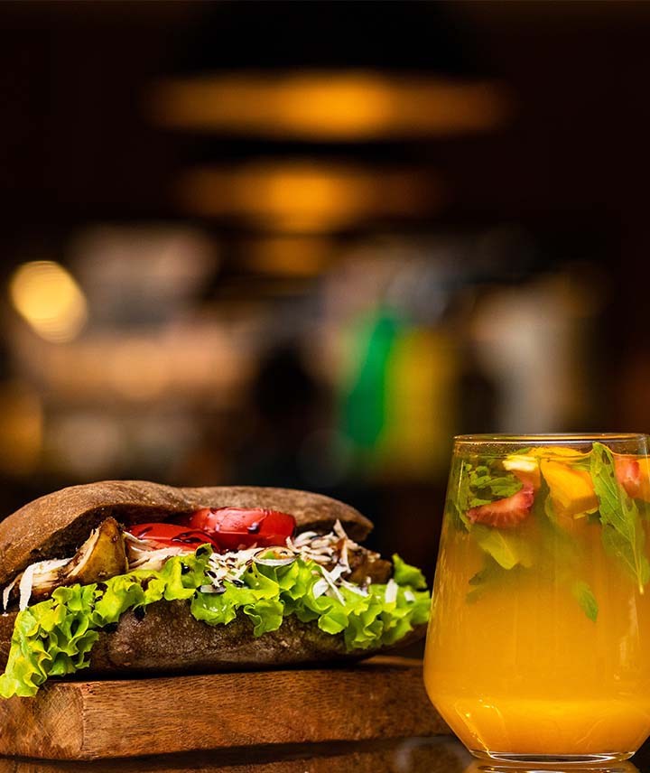 A closeup image of a cocktail and steak sandwich