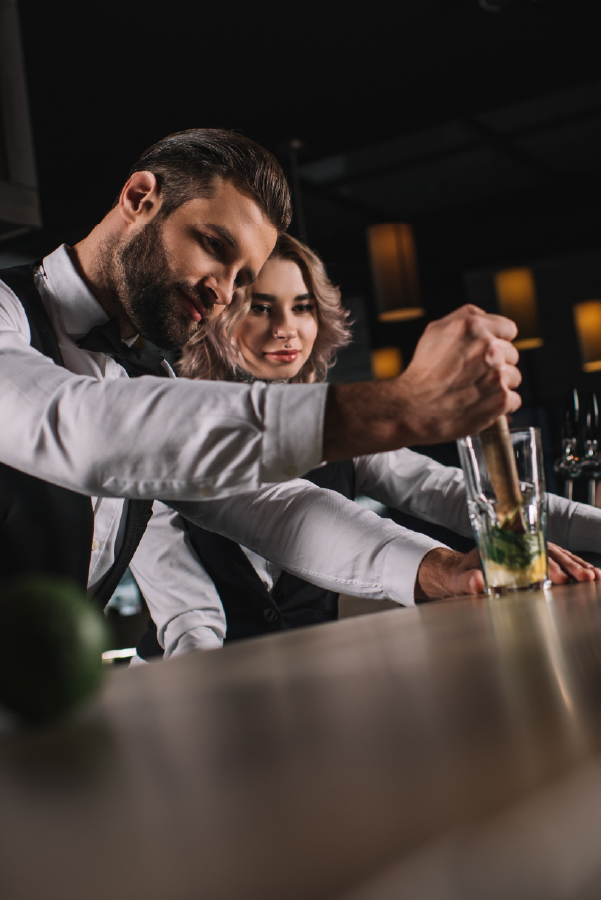bartender colando un coctel al fondo bartender observando