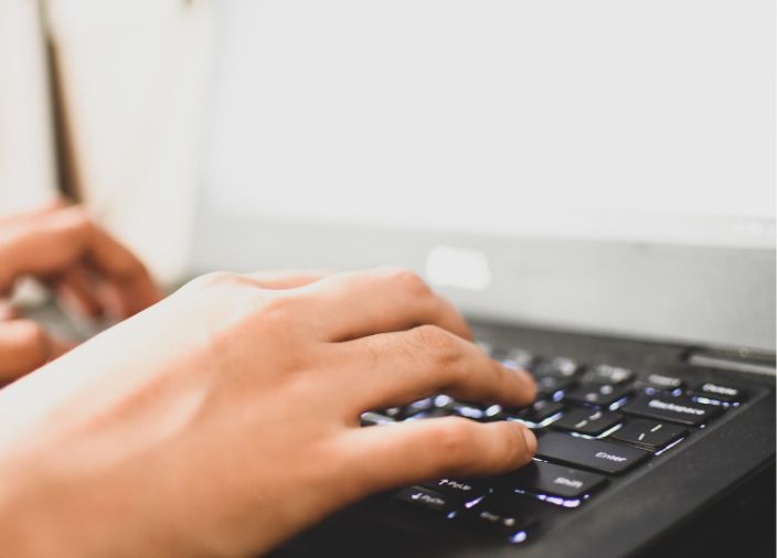 Mãos digitando em um teclado de notebook.
