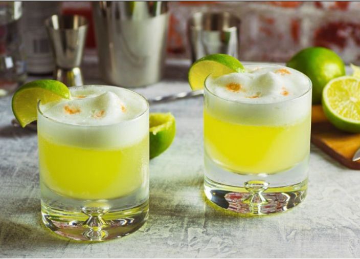 yellow cocktail with foam and lime garnish