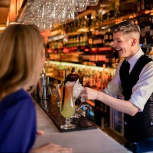 Bartender serving a customer a yellow cocktail