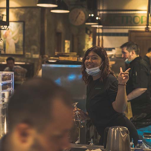 Bartender posing behind bar giving peace sign 