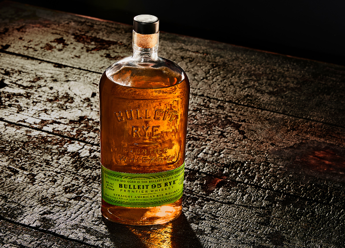 Botella de Bulleit Rye apoyada en una superficie de madera
