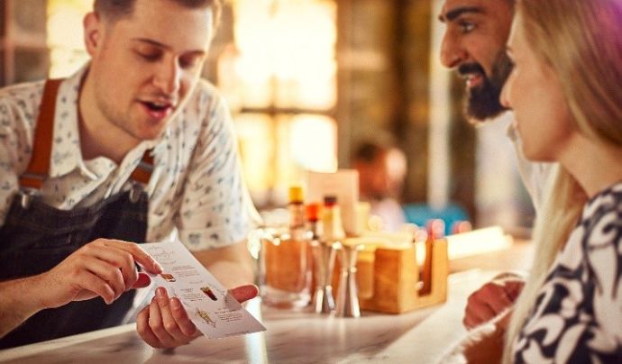 Bar staff showing customer a menu in bar setting 