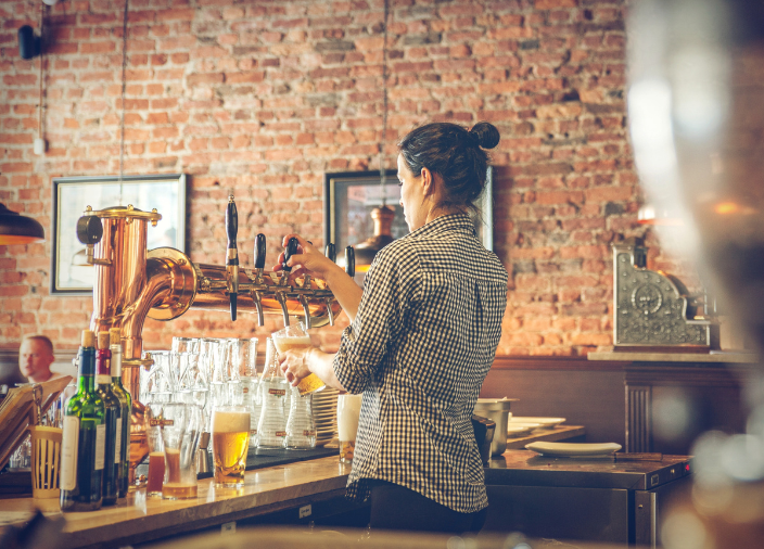  Female bartender pouring beer from tap    