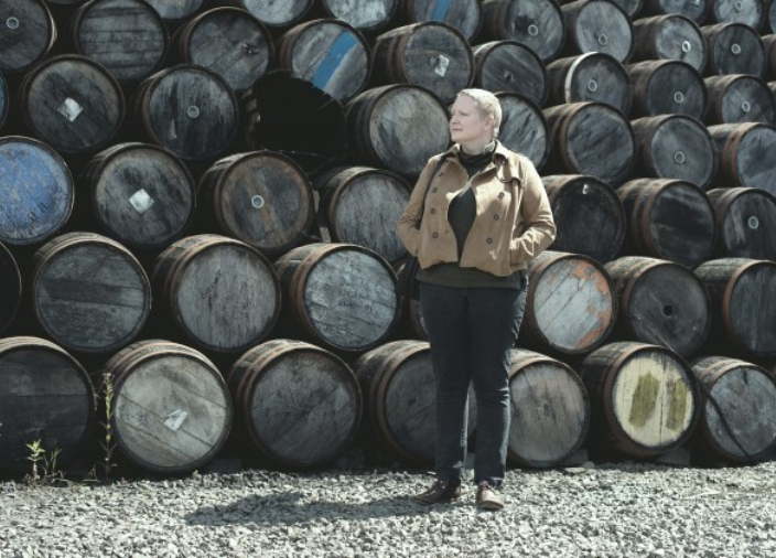 Mujer de pie delante de barricas de whisky