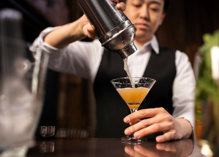Imagem de um bartender passando o líquido para uma taça