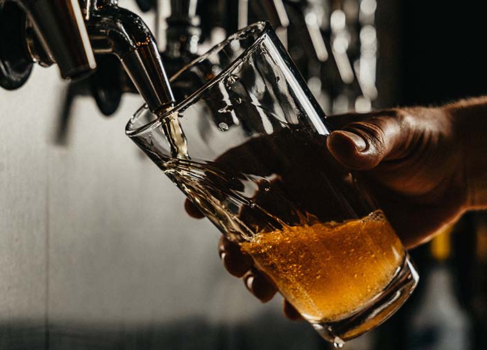 A hand holding a pint glass while the beer is poured 