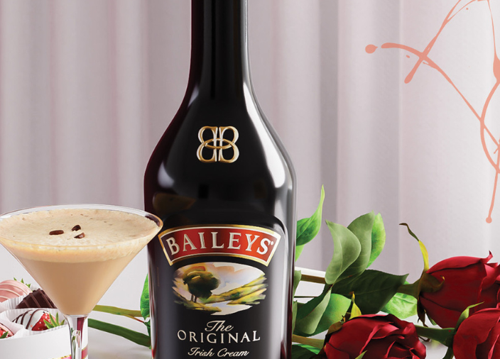 Bailey's-Flasche mit einem Espresso-Martini auf der linken Seite und roten Rosenblättern auf der rechten Seite. 