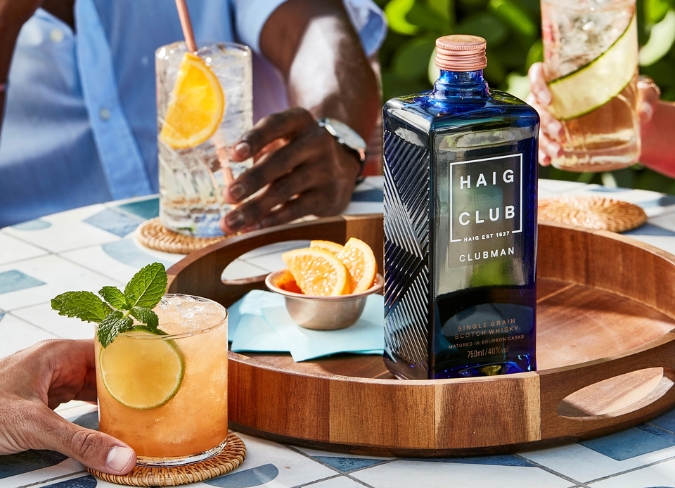 Bottle of Haig Club on tray surrounded by cocktails and garnishes