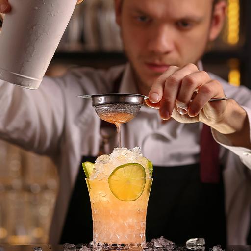 A bartender straining a drink into a glass