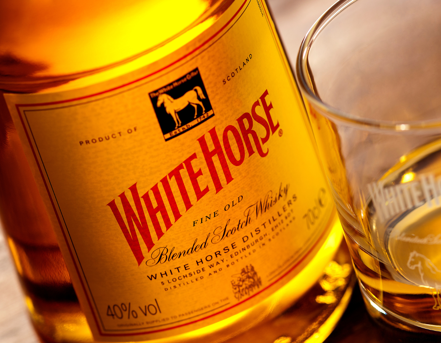 Eine Flasche White Horse Whisky auf einem Tisch neben einem Glas Whisky