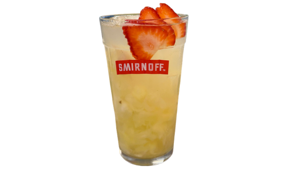 Copo alto com logo Smirnoff, drinque amarelo com gelo e fatias de morango. Fundo branco.