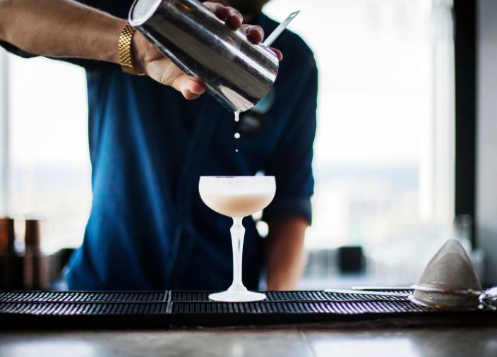 pouring a cocktail from shaker into glass