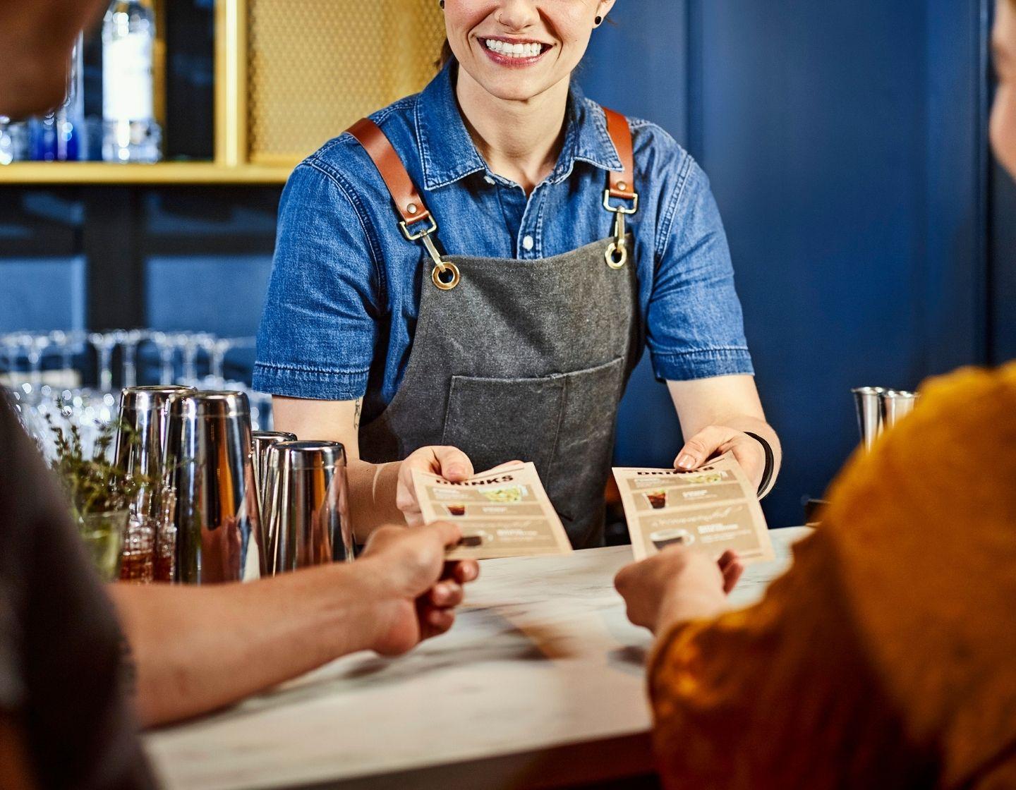 Bartender repartiendo menús de bebidas