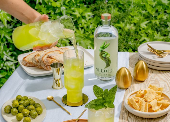 Ein Getränk wird auf einem Tisch mit Speisen in ein Glas gegossen.