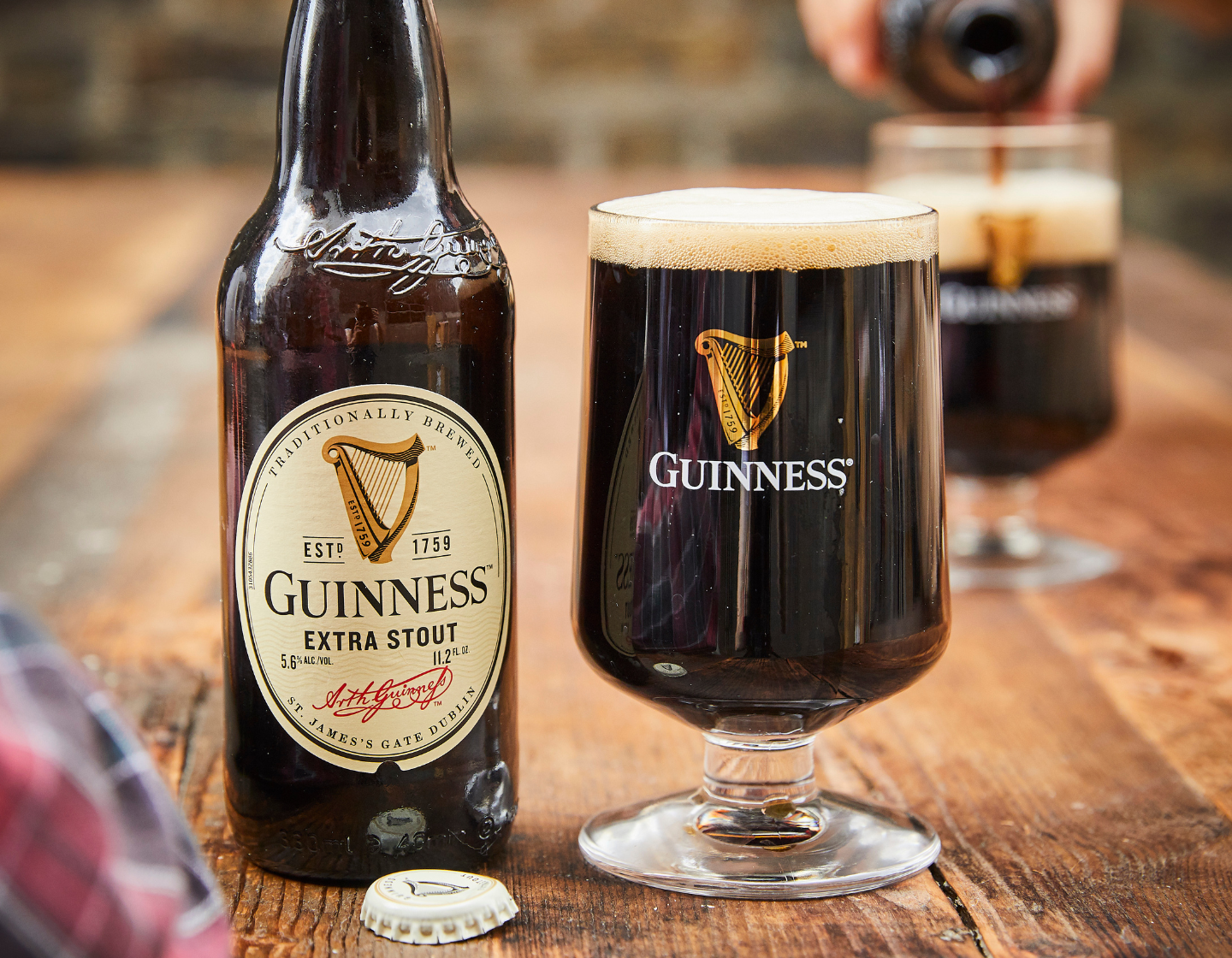 Bottle of Guinness Extra Stout on table beside pint glass filled with Guinness