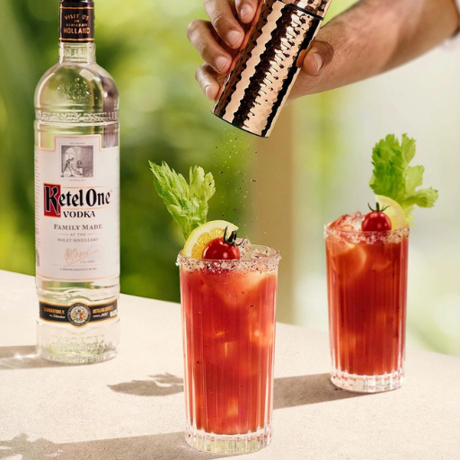 Garrafa de vodka Ketel One sobre a mesa ao lado de dois coquetéis bloody mary