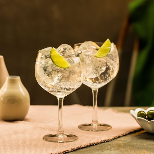 Una imagen de dos copas de gin tonic con hielo y garnish de lima