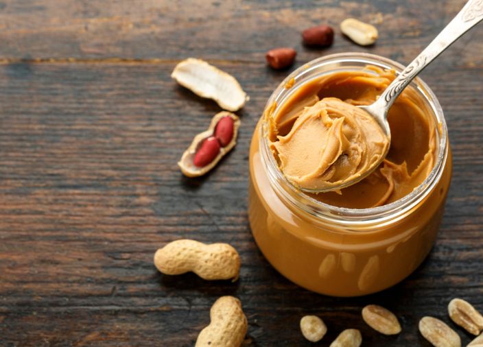 Crema de cacahuete en un frasco abierto y cacahuetes