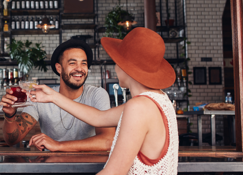 Zwei Personen sitzen an einer Bar und stoßen an
