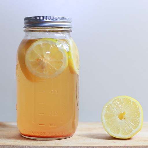 A glass jar filled with liquid and lemon.
