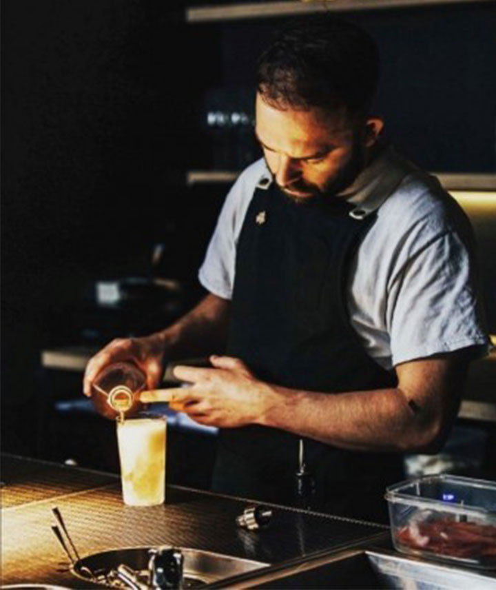 Ein Barkeeper gießt eine Spirituose in ein gefrorenes Cocktailglas.