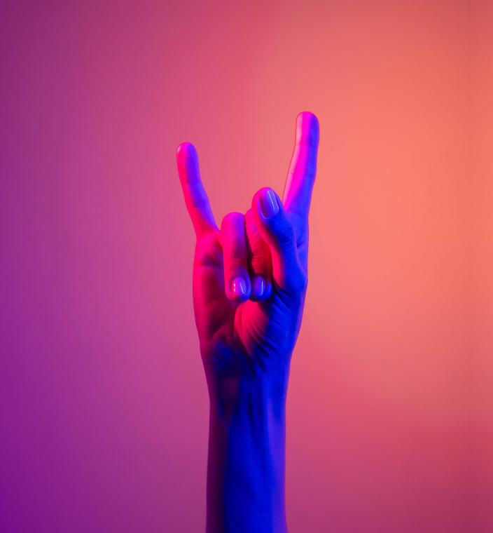 uma mão fazendo o símbolo do rock, conhecido como o &quot;chifre&quot; em um fundo gradiente