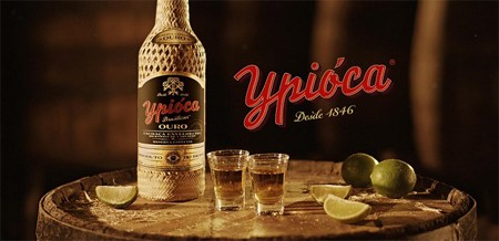 Imagem promocional da garrafa de Ypióca com copos e limões 