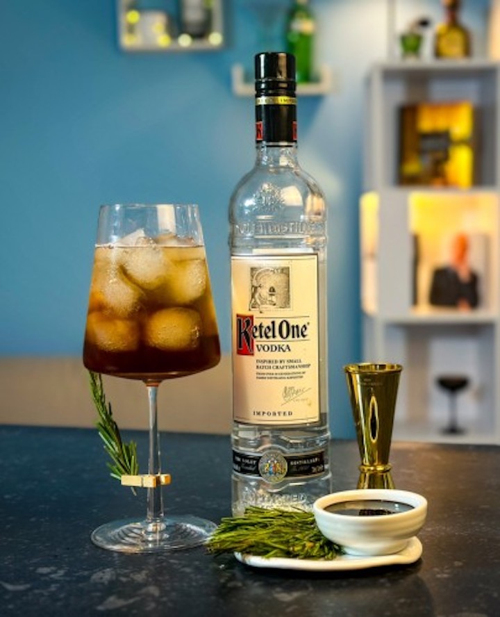 Ein Cocktail steht neben einer Flasche mit Wodka