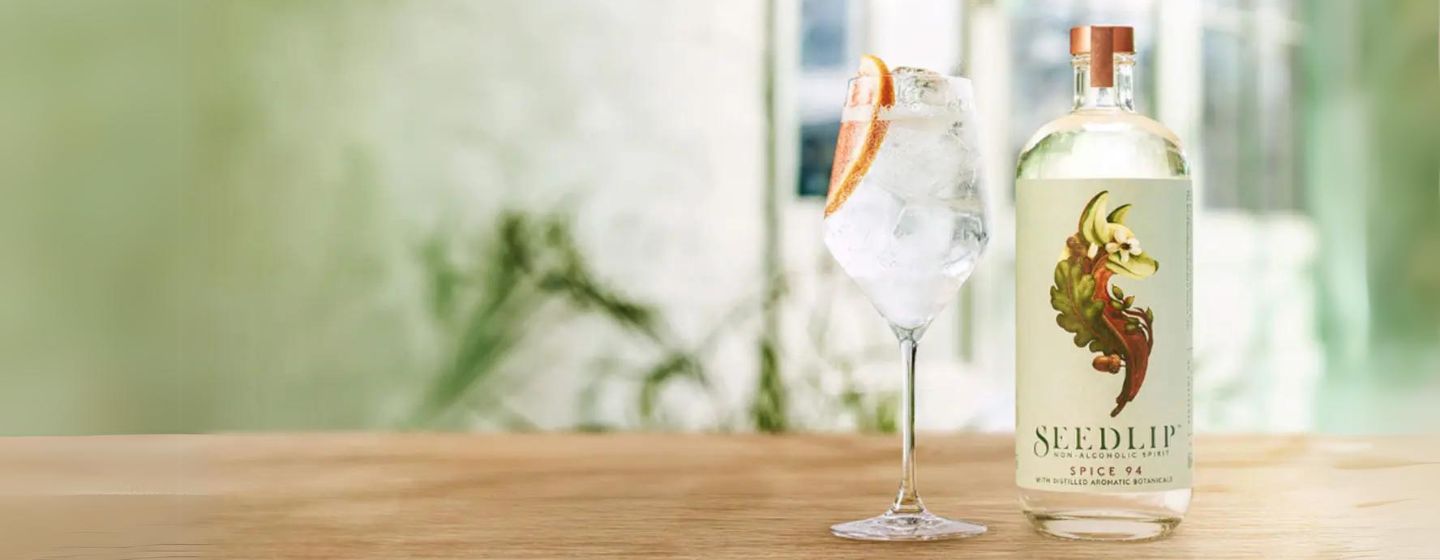 Botella de Seedlip Spice 94 en la mesa junto al cóctel