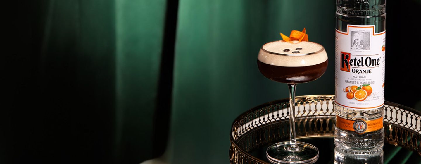 Cocktail in a coupe glass with a bottle of Ketel One